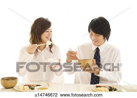 Stock Image - Man and woman eating meal at dining table. Fotosearch