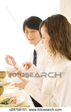 Stock Image - Man and woman eating meal at dining table. Fotosearch