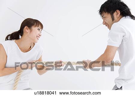 Stock Image - Man and woman playing tug-of-war. Fotosearch