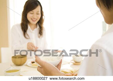 Stock Photo - Man and woman sitting eating meal. Fotosearch