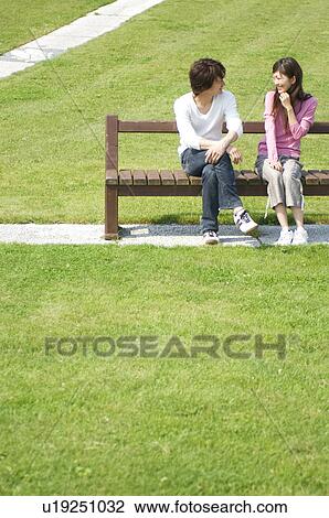 Man and woman sitting together on park bench View Large Photo Image Stock Image - Man and woman sitting together on park bench. Fotosearch