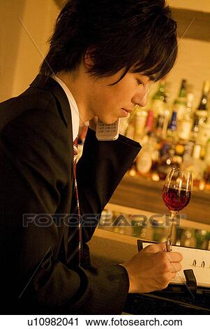Stock Image - Man drinking wine and writing in his business diary. Fotosearch