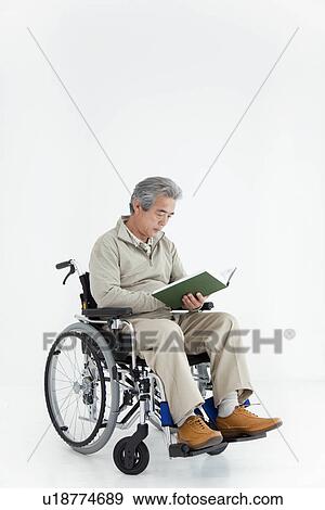 Man in a wheelchair reading a book View Large Photo Image Stock Photo - Man in a wheelchair reading a book. Fotosearch
