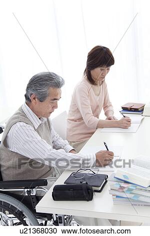 Stock Image - Man in wheelchair and woman studying. Fotosearch