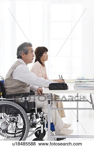 Stock Photo - Man in wheelchair and woman studying. Fotosearch