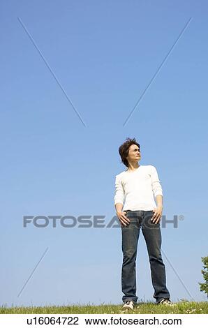 Man standing on grass gazing into distance View Large Photo Image Stock Image - Man standing on grass gazing into distance. Fotosearch