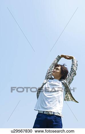 Man standing with arms above head View Large Photo Image Stock Image - Man standing with arms above head. Fotosearch