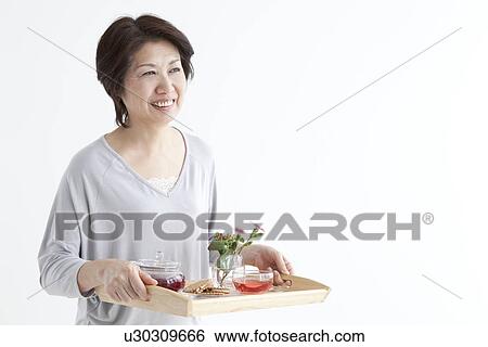 Mature woman carrying a tray of food and tea View Large Photo Image Stock Photograph - Mature woman carrying a tray of food and tea. Fotosearch
