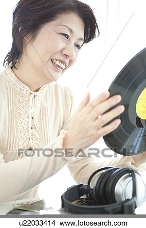 Mature woman holding a vinyl record View Large Photo Image Picture - Mature woman holding a vinyl record. Fotosearch