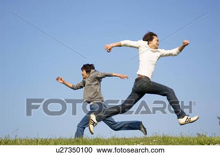 Stock Image - Men running on grass. Fotosearch