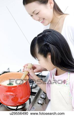 Stock Image - Mother and daughter cooking soup. Fotosearch