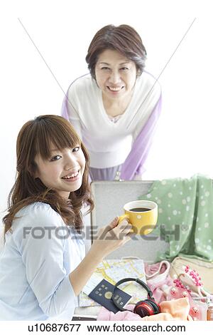 Stock Photo - Mother and daughter drinking coffee on a sofa. Fotosearch
