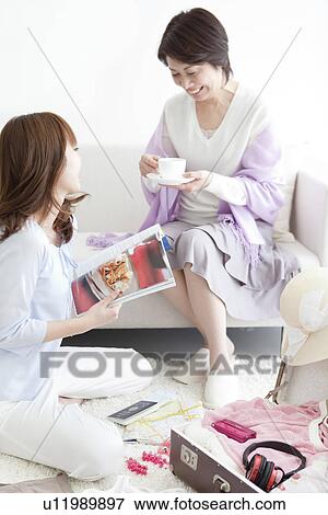Stock Photo - Mother and daughter drinking coffee on a sofa. Fotosearch