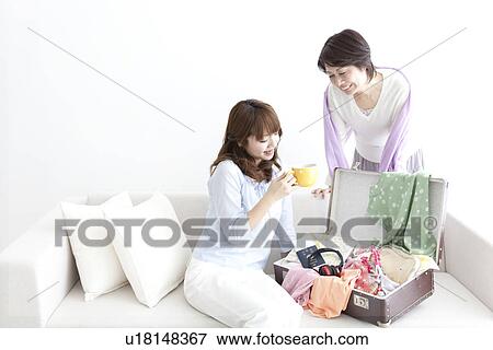 Stock Photo - Mother and daughter drinking coffee on a sofa. Fotosearch