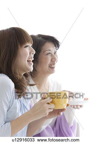 Stock Image - Mother and daughter drinking coffee together. Fotosearch