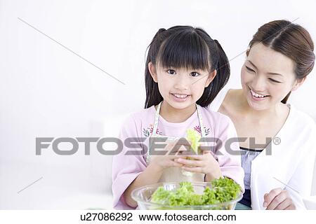 Stock Image - Mother and daughter making salad. Fotosearch