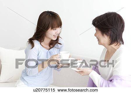Mother and daughter sitting on sofa and drinking coffee View Large Photo Image Stock Photography - Mother and daughter sitting on sofa and drinking coffee. Fotosearch