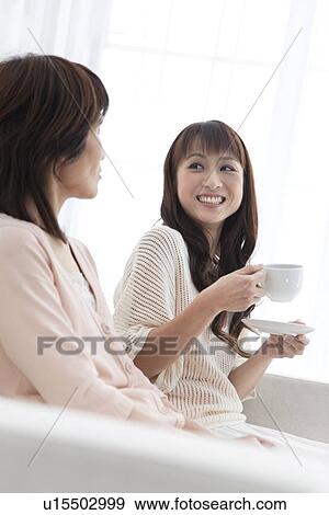 Stock Photo - Mother and daughter sitting on sofa. Fotosearch