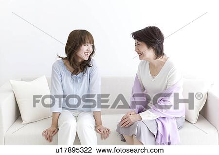 Mother and daughter sitting together on a sofa View Large Photo Image Stock Image - Mother and daughter sitting together on a sofa. Fotosearch