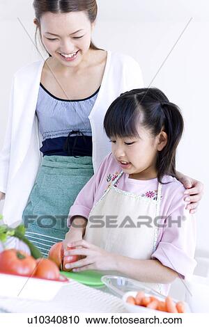 Stock Image - Mother and daughter slicing tomatoes. Fotosearch