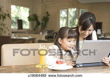 Stock Photo - Mother and daughter using laptop at a cafe. Fotosearch