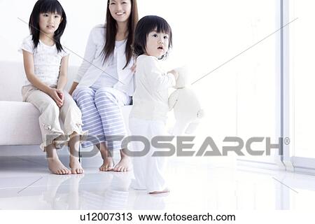 Stock Image - Mother and daughter watching baby girl with teddy. Fotosearch