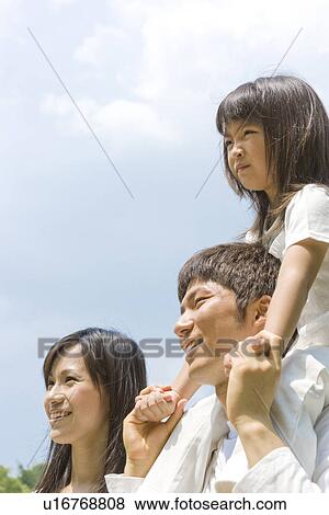 Stock Photo - Mother and father carrying daughter on his shoulders. Fotosearch