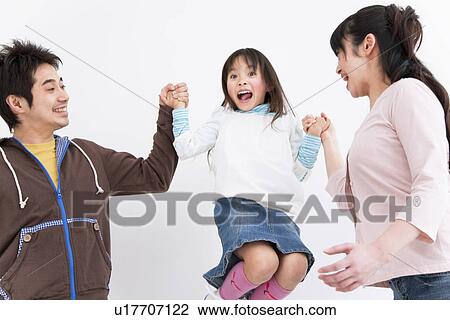 Stock Image - Mother and father lifting up daughter. Fotosearch