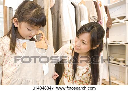 Mother and little girl clothes shopping together View Large Photo Image Stock Photo - Mother and little girl clothes shopping together. Fotosearch