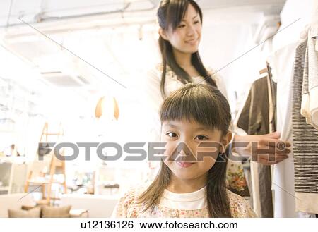Stock Photograph - Mother and little girl clothes shopping together. Fotosearch