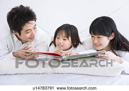 Mother, father and daughter lying on bed reading picture book View Large Photo Image Stock Image - Mother, father and daughter lying on bed reading picture book. Fotosearch