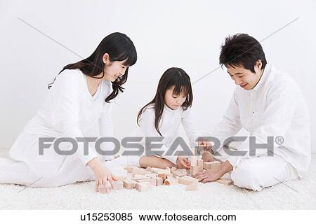 Stock Photography - Mother, father and daughter playing with blocks on a rug. Fotosearch