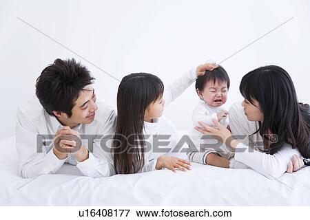 Stock Photo - Mother, father and daughter trying to comfort crying baby boy. Fotosearch