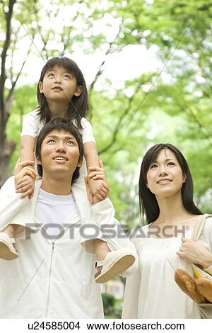 Picture - Mother, father and daughter walking through park. Fotosearch