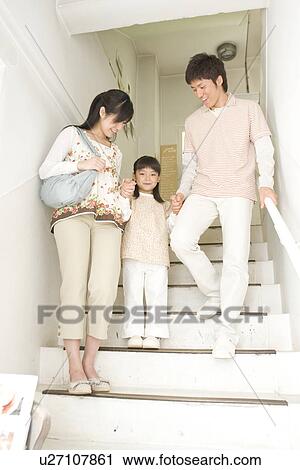 Stock Image - Mother, father and daughter walking down staircase. Fotosearch