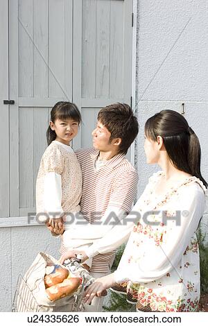 Stock Photograph - Mother, father and daughter walking with groceries in bicycle basket. Fotosearch