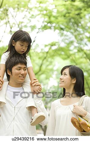 Stock Photograph - Mother, father and daughter walking through park. Fotosearch