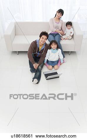 Mother, father, daughter and baby boy in living room with a laptop View Large Photo Image Stock Image - Mother, father, daughter and baby boy in living room with a laptop. Fotosearch