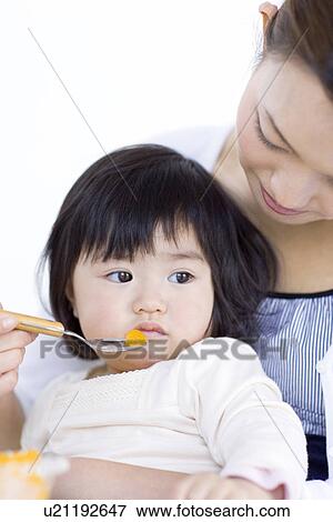 Mother feeding baby daughter fruit salad View Large Photo Image Stock Photo - Mother feeding baby daughter fruit salad. Fotosearch