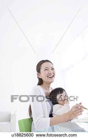 Mother feeding baby daughter View Large Photo Image Stock Image - Mother feeding baby daughter. Fotosearch