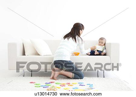Mother feeding her baby on the couch View Large Photo Image Stock Image - Mother feeding her baby on the couch. Fotosearch