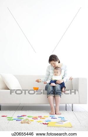 Mother feeding her baby on the couch View Large Photo Image Stock Photograph - Mother feeding her baby on the couch. Fotosearch