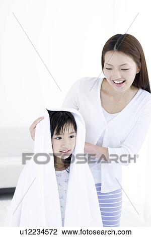 Stock Image - Mother helping to dry daughter's hair with a towel. Fotosearch