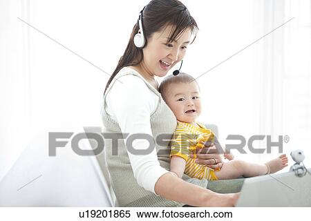 Mother holding her baby and using laptop View Large Photo Image Stock Photography - Mother holding her baby and using laptop. Fotosearch