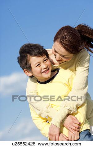 Mother hugging her son against a blue sky View Large Photo Image Stock Photograph - Mother hugging her son against a blue sky. Fotosearch