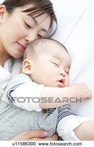 Stock Image - Mother lying with her sleeping baby. Fotosearch