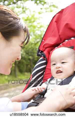 Picture - Mother playing with her baby in stroller. Fotosearch