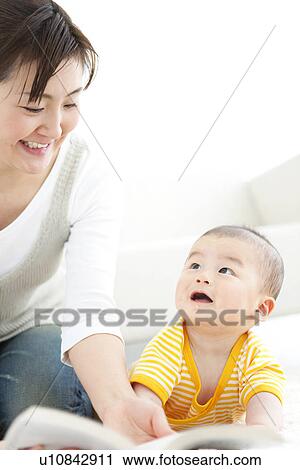 Stock Image - Mother reading a book to her baby. Fotosearch