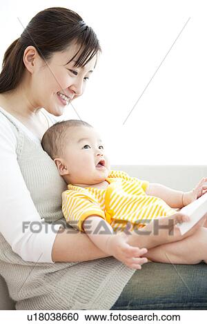 Stock Image - Mother reading a book to her baby. Fotosearch