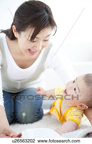 Stock Image - Mother reading a book to her baby. Fotosearch